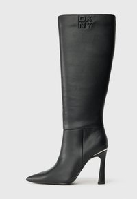Černé kožené vysoké stiletto kozačky s špičatou špičkou a embosovaným logem DKNY blízko horního okraje na jednobarevném pozadí.