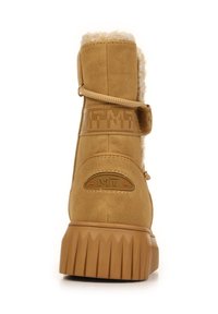 Tan winterboot met dikke geribbelde zool, zachte voering, verstelbare riem rond de enkel en "MT" logo op de hiel.