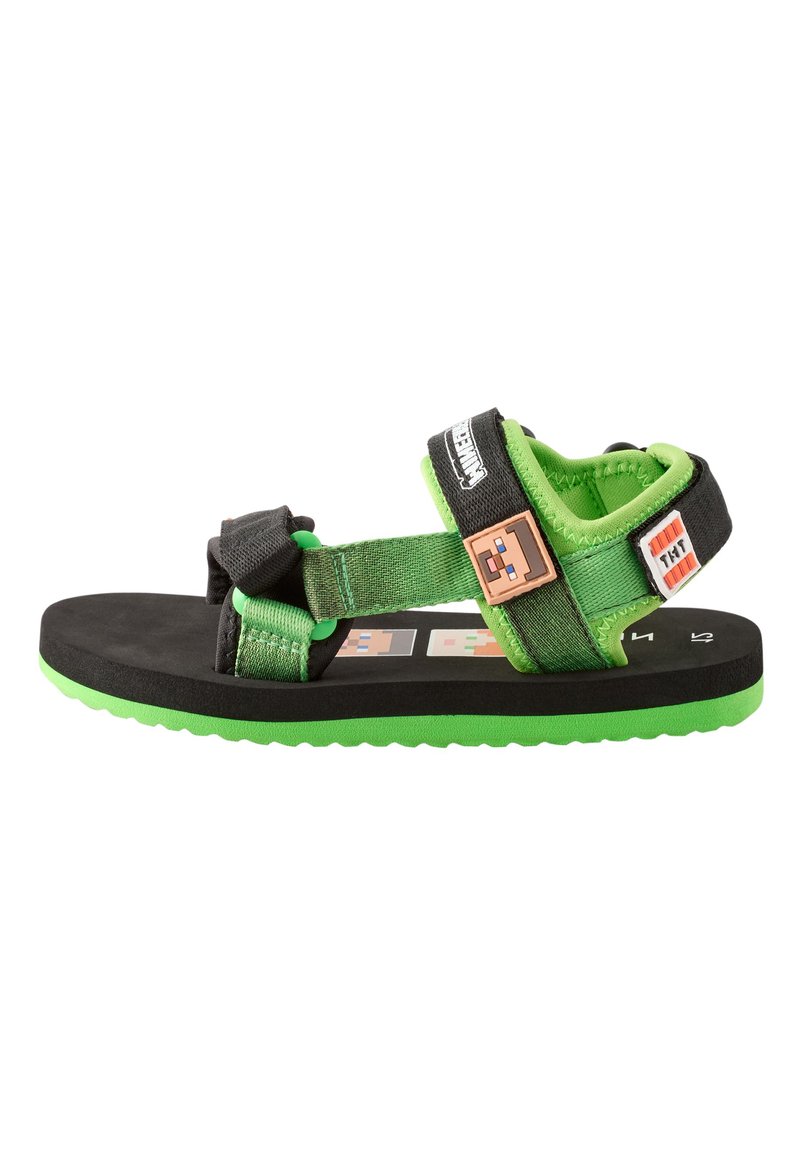 Groene en zwarte sandalen met verstelbare banden, een geribbelde zool en karakteraccenten op het voetbed, ontworpen voor comfort en stabiliteit.