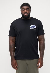 Zwarte katoenen t-shirt met korte mouwen, voorzien van een blauwe golfafbeelding en Japanse tekst op de borst. Standaard pasvorm met ronde halslijn.