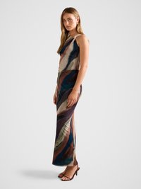 Sleeveless dress with abstract multi-colored pattern in earthy tones. Smooth fabric, fitted silhouette, and side slit. Brown strappy heels.