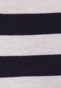 Rayures horizontales en tissu tricoté alternant entre bleu marine foncé et blanc, avec un motif tissé texturé visible.