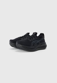 Black athletic shoes with textured fabric upper, rounded toe, black laces, and cushioned soles featuring a subtle logo detail.