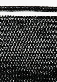 Schwarzer gewebter Stoff mit komplexem Muster, glatter Textur und glänzendem Finish, ergänzt durch einen geflochtenen schwarzen Griff.