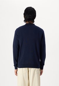 Mörkblå långärmad tröja med rund halsringning och ribbade muddar, uppvisad bakifrån, med en mjuk textur och avslappnad passform.