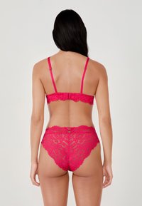 Bralette in pizzo e mutandine coordinate in un vivace rosa. Presenta bordi scallop e motivi floreali, con spalline regolabili e chiusura posteriore.