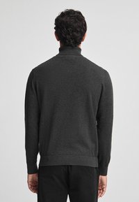 Pullover grigio scuro con collo alto, maniche lunghe e orlo a coste. Realizzato in un morbido tessuto testurizzato. Senza motivi visibili.