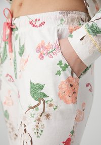 Lightweight pajama pants made of cotton, featuring a floral pattern in pink, green, and beige, with a drawstring waistband and side pockets.
