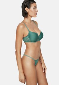 Teal beha en string set. De beha heeft padded cups met kantdetails, verstelbare bandjes en een gouden accent. De string heeft dunne bandjes en een kanten rand.