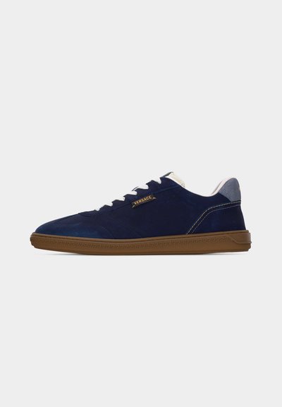 Baskets en daim bleu marine Versace avec lacets blancs, semelle gomme ornée d'un motif clé grecque, et col de talon gris clair contrastant.