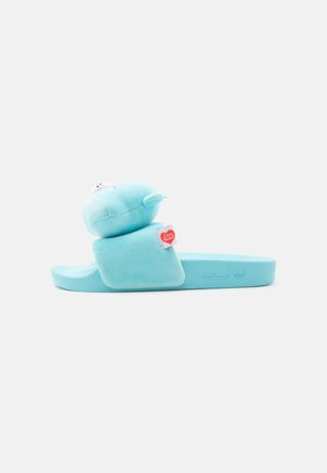 Sandale slide bleu clair avec un personnage en peluche Care Bears attaché à la sangle et une étiquette Care Bears sur le côté.