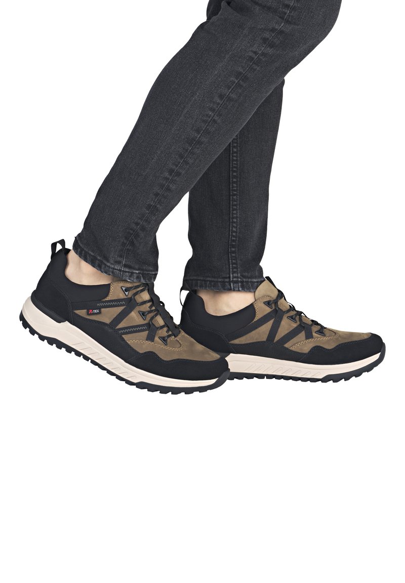 Scarpe sportive nere e marroni con una superficie texture, design con lacci, collo imbottito e suola bianca con scanalature profonde per una buona aderenza.