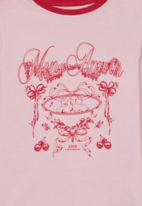 Világos rózsaszínű póló piros grafikai designnal, amelyen "Mon Amour" felirat, virágos díszítések, egy dekoratív tál, két állat és cseresznye található.