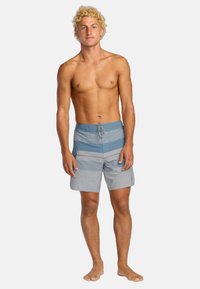 Pánske plavky v rôznych odtieňoch modrej a šedej s horizontálnymi pruhmi, elastický pás a detail sťahovacej šnúrky. Ľahký materiál.