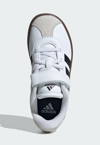 Biały but sportowy z czarnymi paskami, zamszowymi akcentami i paskiem na rzep. Posiada wyściełany kołnierz i teksturowaną podeszwę.