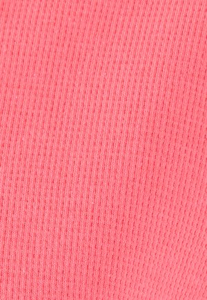 Tissu rose avec une texture côtelée verticale en tricot, des côtes uniformément espacées créant une surface douce et flexible.