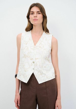 Mouwloze vest in witte stof met een bloemenpatroon in beige. Opvallende details zijn een V-hals, vijf knopen en twee zijzakken.