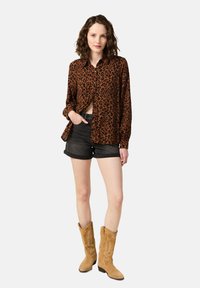 Brun leopardmönstrad skjorta med knappar, svarta denimshorts och bruna cowboystövlar med dekorativ sömnad. Enkelt, avslappnat klädesdesign.