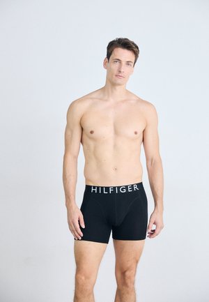 Schwarze Boxershorts mit einem weißen "HILFIGER"-Logo-Bund, aus weichem Material gefertigt, mit einer engen Passform und einem Design bis zur Mitte des Oberschenkels.
