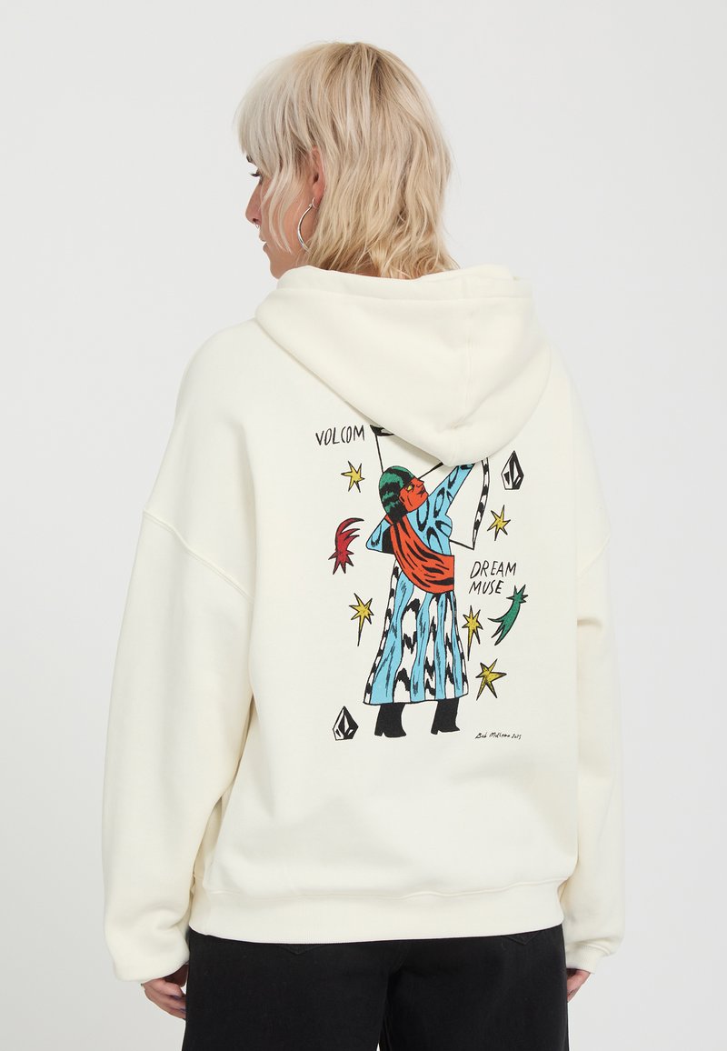 Personne blonde portant un sweat à capuche blanc avec une illustration colorée d'une silhouette en manteau bleu et écharpe rouge dans le dos.