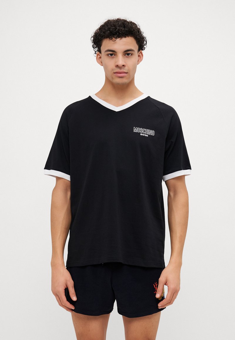 T-shirt preto de mangas curtas com decote V e detalhes brancos nas mangas, apresentando o logotipo da Moschino no peito. Material macio e leve.