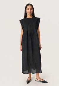 Schwarzes, ärmelloses Maxikleid mit Rüschenschultern, gerafftem Oberteil und gestuftem Rock. Strukturiertes Gewebe mit leichter, durchsichtiger Qualität.