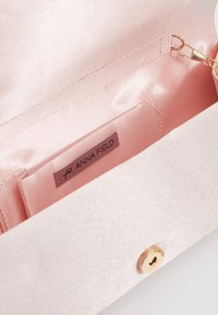 Różowa satynowa torebka w środku z metką "Anna Field", z magnetycznym zapięciem i małym złotym łańcuchem.