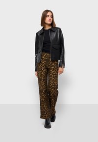 Black leather zip-up jacket, fitted black top, leopard print wide-leg trousers in brown and black, paired with black chunky boots.