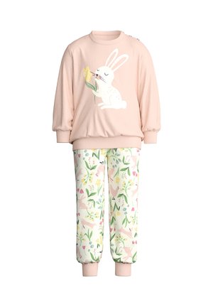 Roze kindertrui met konijntje dat een gele bloem vasthoudt en een witte broek met kleurrijk bloemen- en konijnenpatroon.