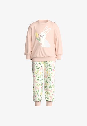 Sweat-shirt rose pour enfants avec un lapin tenant une fleur jaune, et un pantalon blanc avec un motif floral coloré et des lapins.
