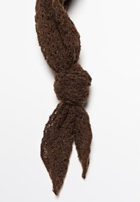 Brun stickad scarf med ett texturerat, spetsliknande mönster, knuten i mitten med spetsiga ändar, lämplig för olika stylingalternativ.