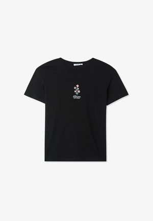 Maglietta nera in cotone con maniche corte e scollo rotondo. Ricamo floreale centrato in rosa e verde con il testo "Fiorisci con Grazia."