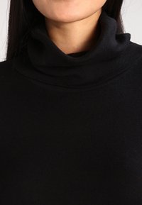 Schwarzer Rollkragenpullover mit einer dicken, gerippten Textur, glattem Stoff und einem eng anliegenden Kragen. Keine sichtbaren Muster oder Akzente.