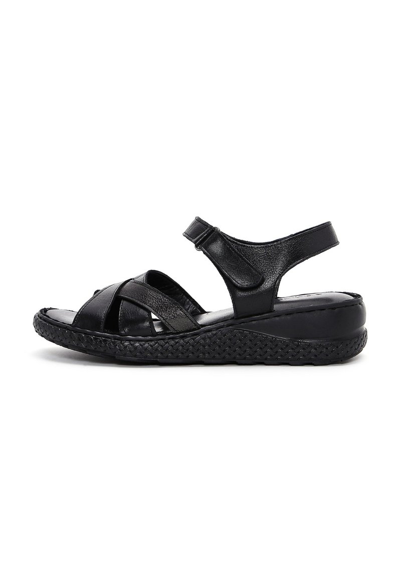Sandal in pelle nera con cinturini incrociati, cinturino alla caviglia regolabile, suola testurizzata e bordatura intrecciata. Piattaforma bassa per il comfort.
