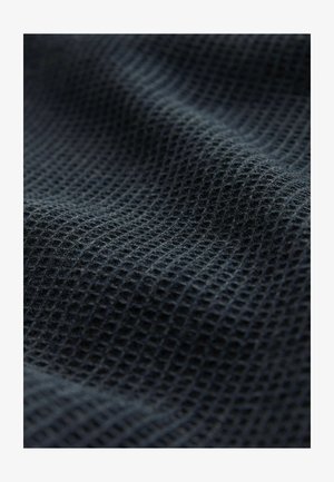 Tamno siva teksturirana tkanina s uzorkom rešetke, s mekim i lagano rastezljivim tkanjem, pogodna za različite tekstilne primjene.