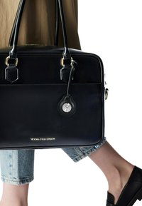 Borsa a tracolla nera in pelle con hardware dorato, dotata di un orologio da tasca rotondo nero attaccato. Superficie testurizzata e design elegante.