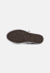 Suela de zapato de goma marrón con patrón de diamante, borde blanco y logotipo. Textura lisa con punta redondeada y acentos laterales.