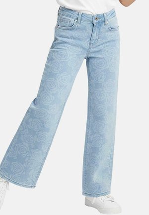 Lichtblauwe wijde jeans met rozenpatroon, vijf zakken, riemlussen en witte stiksels; gecombineerd met witte sneakers.