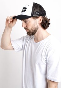 Trucker hat with a black mesh back and white front, featuring a black rectangular patch logo, curved brim, and adjustable snapback closure.