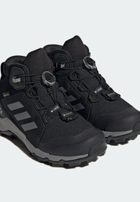 Zapatos de senderismo negros con parte superior de malla y material sintético, sistema de cordones seguro, detalles en gris y suela de tracción robusta. Material impermeable Gore-Tex.