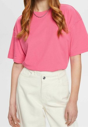 Felroze T-shirt met korte mouwen van katoen, gecombineerd met hoog waisted witte denim jeans met een voorknopsluiting en zakken.