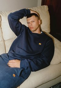 Navy blue sweatshirt and sweatpants made of thick fabric, featuring an embroidered orange elephant logo on the left chest and thigh.