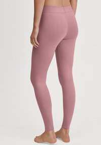 Leggings roses en tissu doux, avec une coupe ajustée, une taille sans couture et un design long. Sans motifs ni quincaillerie visibles.