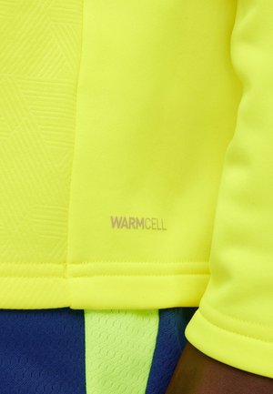 Top sportivo giallo brillante realizzato in tessuto strutturato con motivi geometrici, caratterizzato da un'etichetta "WARMCELL" e rifinito con sezioni blu e verdi.
