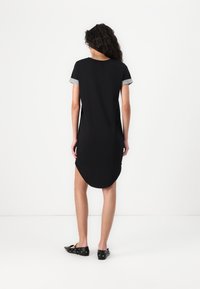 Svart klänning med korta ärmar som har grå manschetter, rundad fåll och sprund i sidorna. Tillverkad av mjukt tyg, designen är enkel och strömlinjeformad.