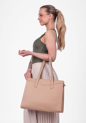 Béžová taška přes rameno s dvojitými horními uchy, strukturovaný design, hladká textura, se šitým logem, umístěná na světlém pozadí.