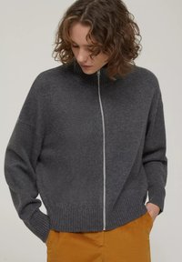 Grauem Reißverschluss-Pullover mit hohem Kragen, gerippten Bündchen und Saum sowie lockerer Passform. Aus weichem Material mit einer subtilen Textur hergestellt.