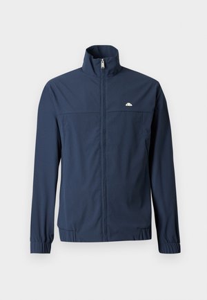 Lahka temno modra jakna z zadrgo po celotni sprednji strani, visokim ovratnikom, elastičnimi manšetami in majhnim belim logotipom na levi strani prsnega dela.