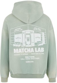 Sudadera verde menta con un gráfico frontal de un café con texto, bolsillo canguro y capucha con cordón. Material de algodón suave.