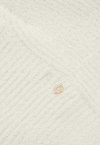 Witte gebreide trui met een zachte textuur, voorzien van een zigzagpatroon en een kleine gouden logo-accent.